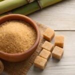 brown-sugar-cubes-and-granulated-sugar-in-wooden-bowl-with-sugarcane-stalks-on-light-wood-background-free-photo